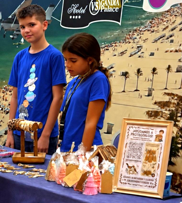 Alec y Shara atendiendo su puesto con pulseras, velas y un cartel para seguirles en Instagram